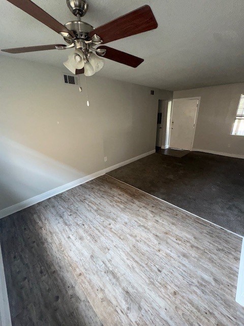 A room with a ceiling fan and wood flooring.